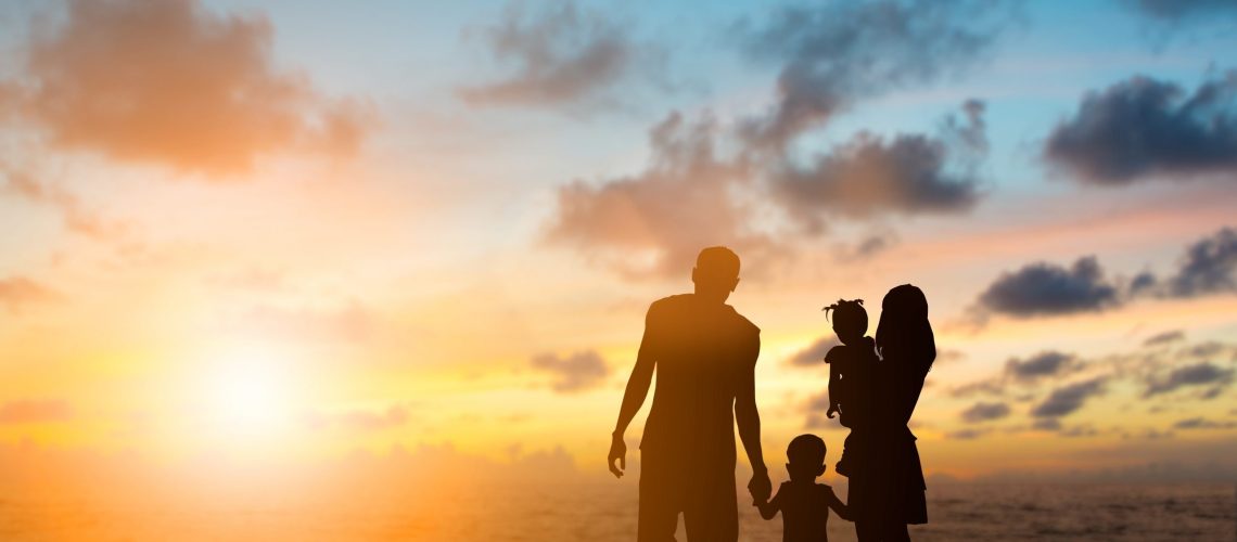 Silhouette family mother, father and young son holding hands, taking a swim in the sea for the first time the children are excited and delighted over blurred beautiful nature.Concept friendly family.flare light.selected focus