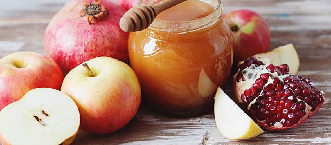 Pomegranate, honey and apple on the old wooden background, traditional food of Rosh Hashana, jewish New Year celebration, copy space